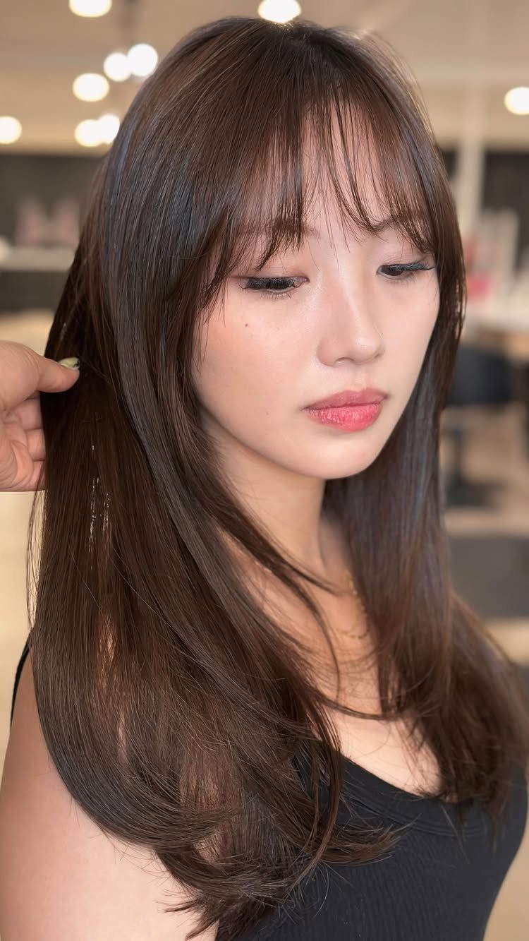 Woman showing wispy bangs blending into long, graduated face-framing layers