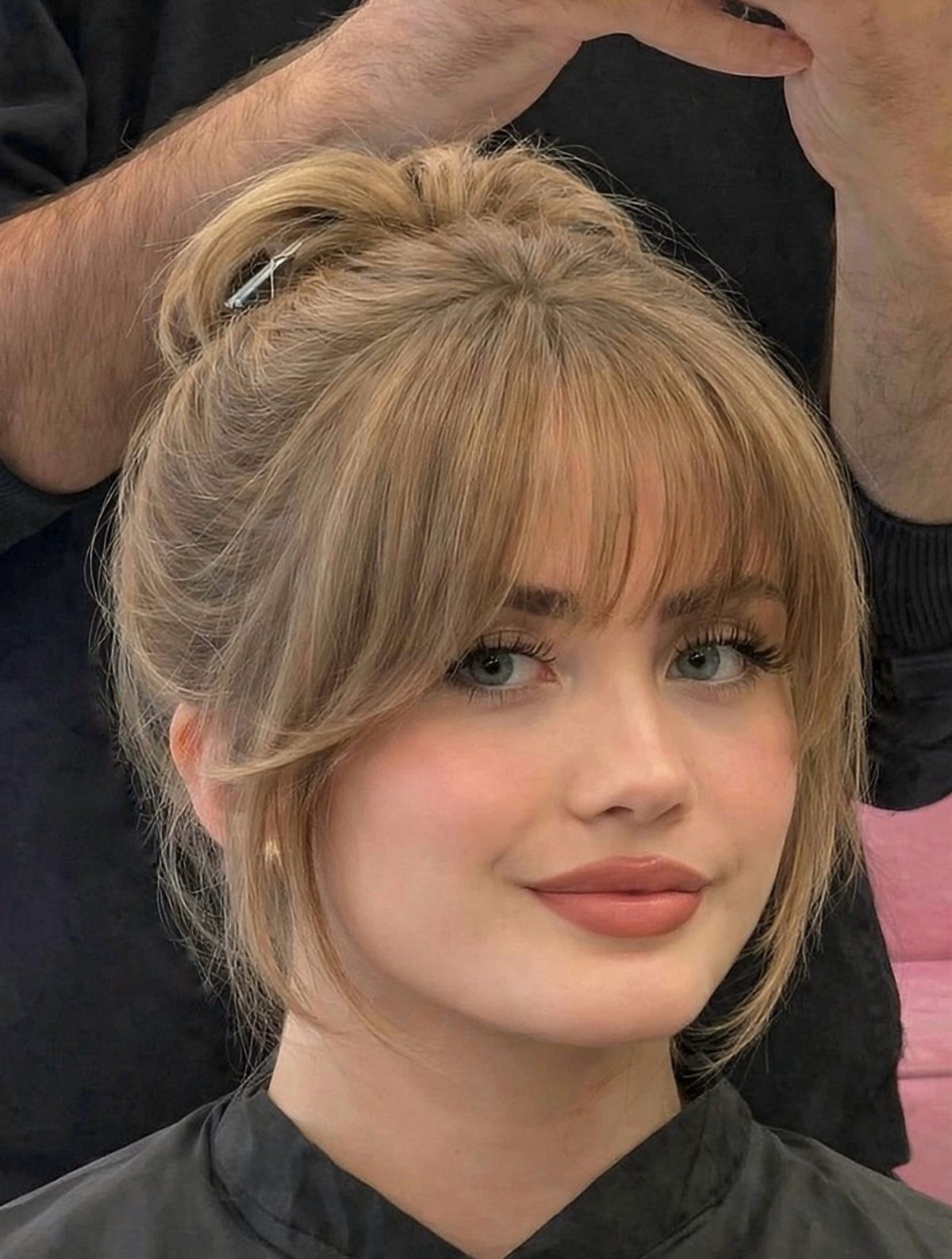 Woman with blonde updo and soft lash-grazing bangs in a salon
