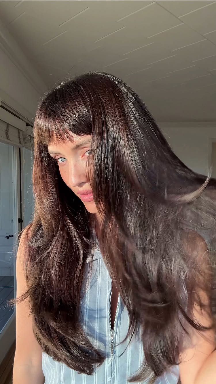 Person with long dark hair and a short, rounded fringe across the forehead