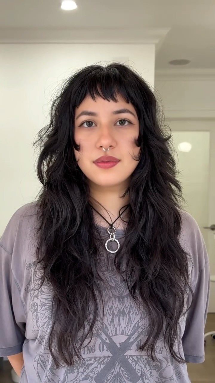 Person with long, textured dark layers and lightweight choppy bangs
