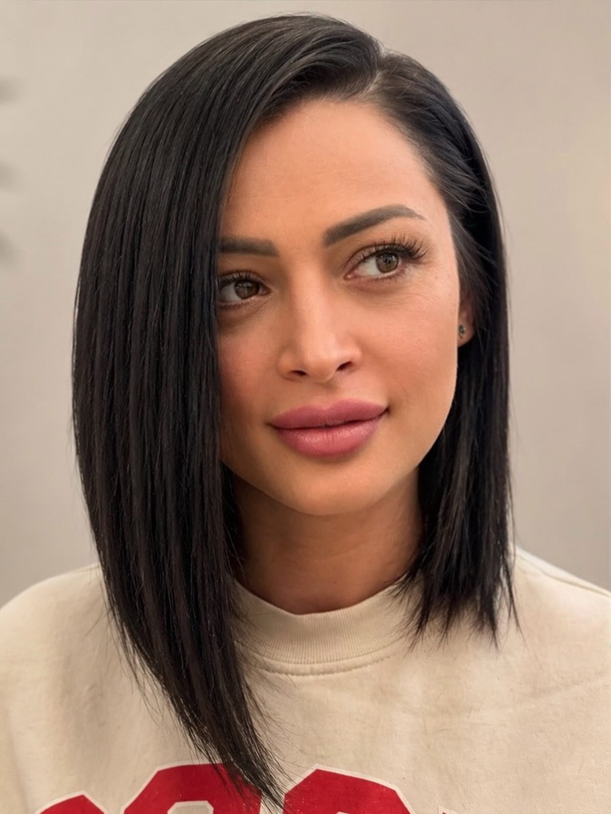 Woman models a sleek asymmetrical bob with a deep side part.