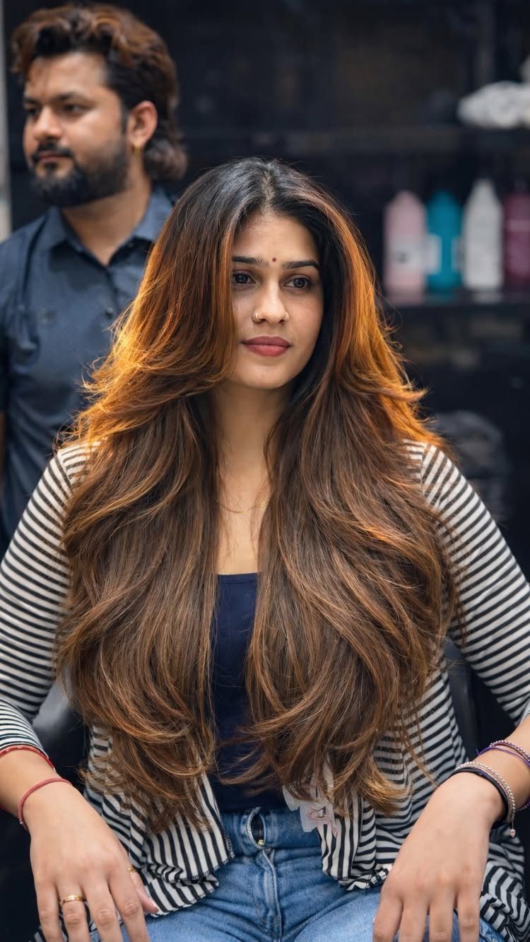 Woman displaying long brown layers with voluminous waves and face-framing strands