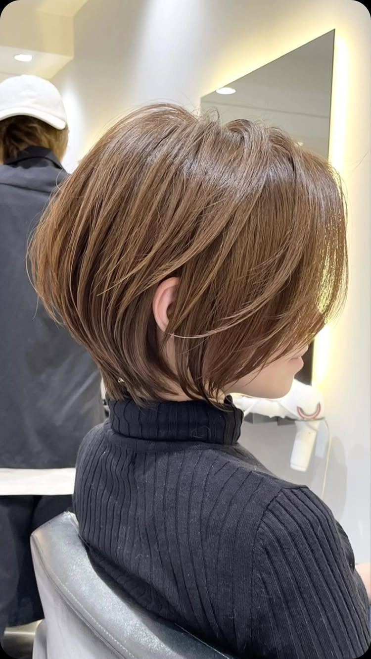 Layered brown textured bob with side-swept fringe in a salon