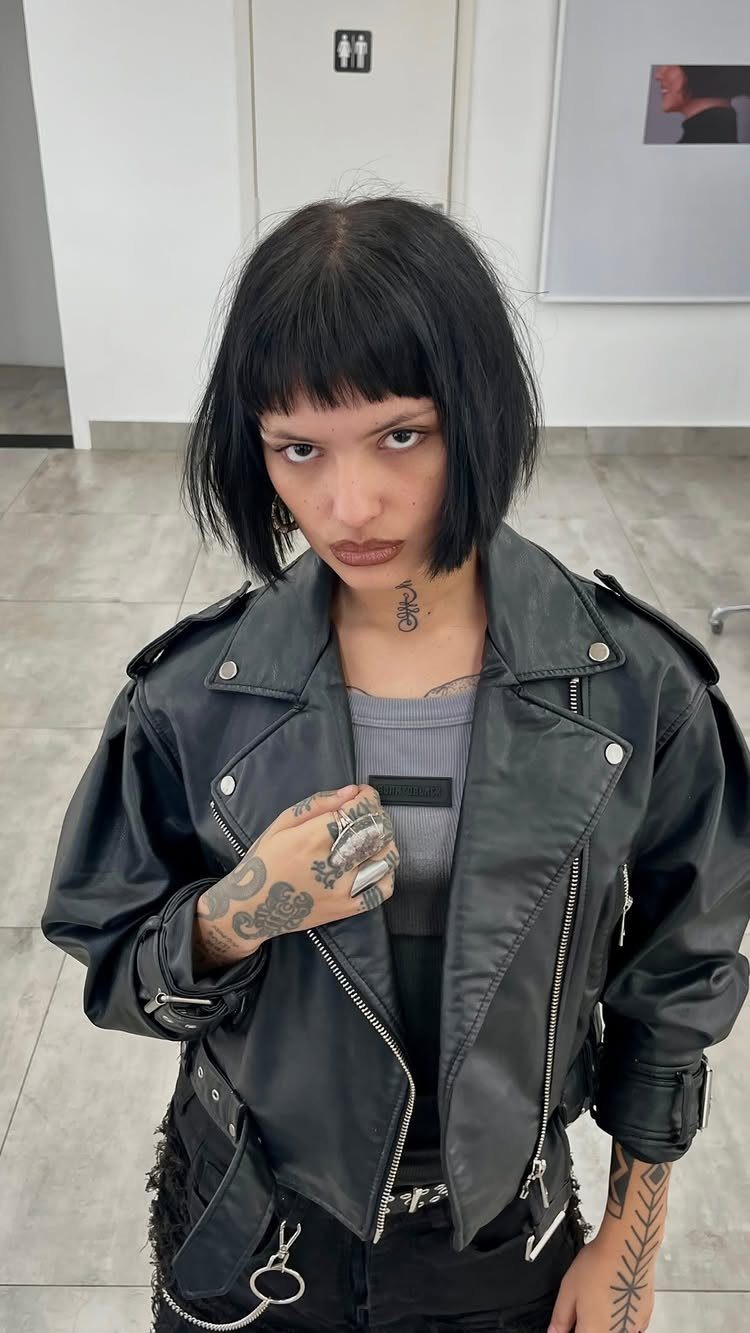 Person with a blunt black bob and straight bangs wearing a leather jacket