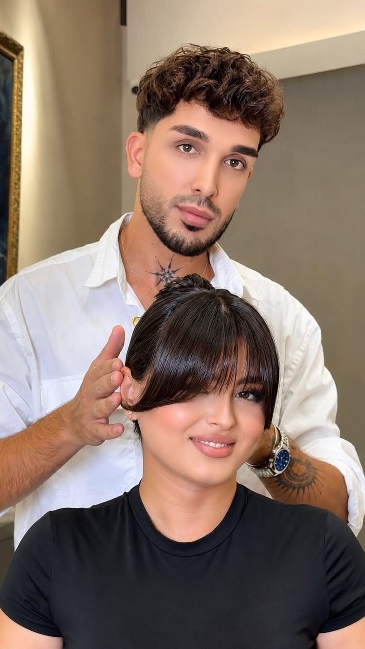 Woman with straight dark hair and eyebrow-grazing bangs seated before a man