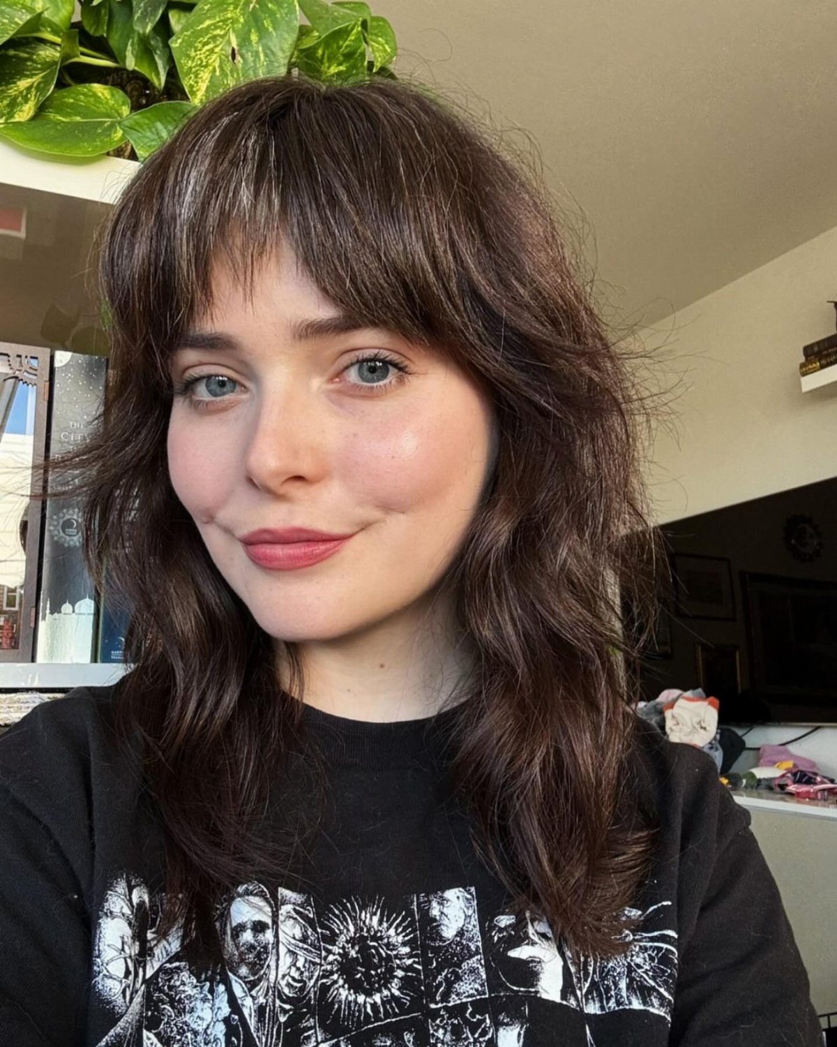 Woman with layered medium-length wavy hair and wispy bangs