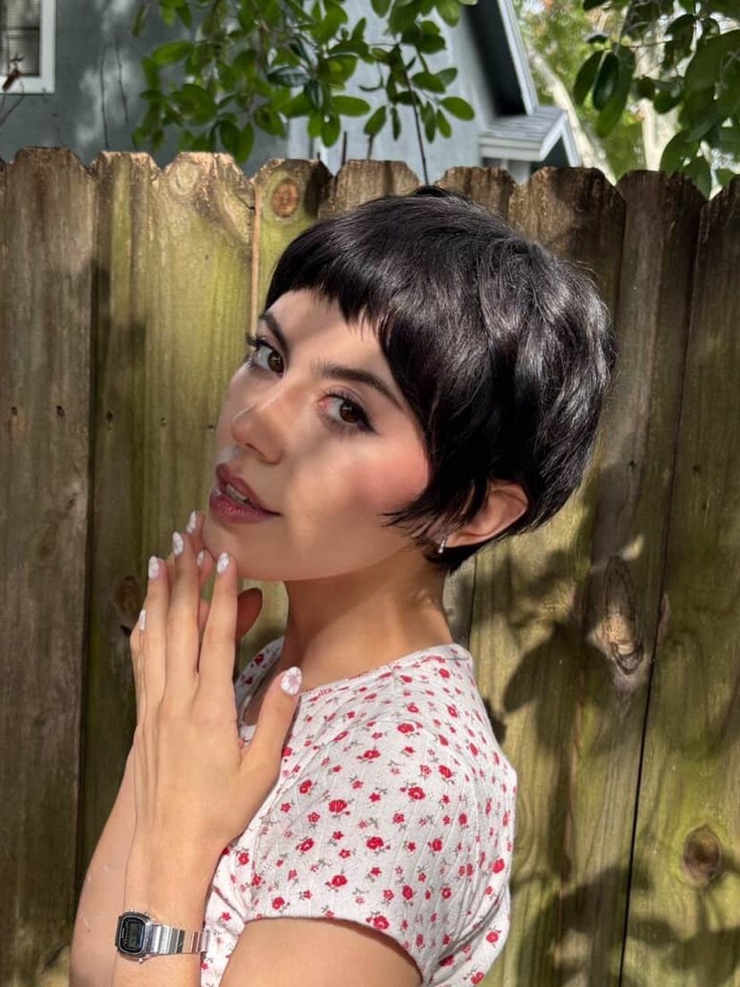 Woman showing a short dark pixie haircut with blunt bangs