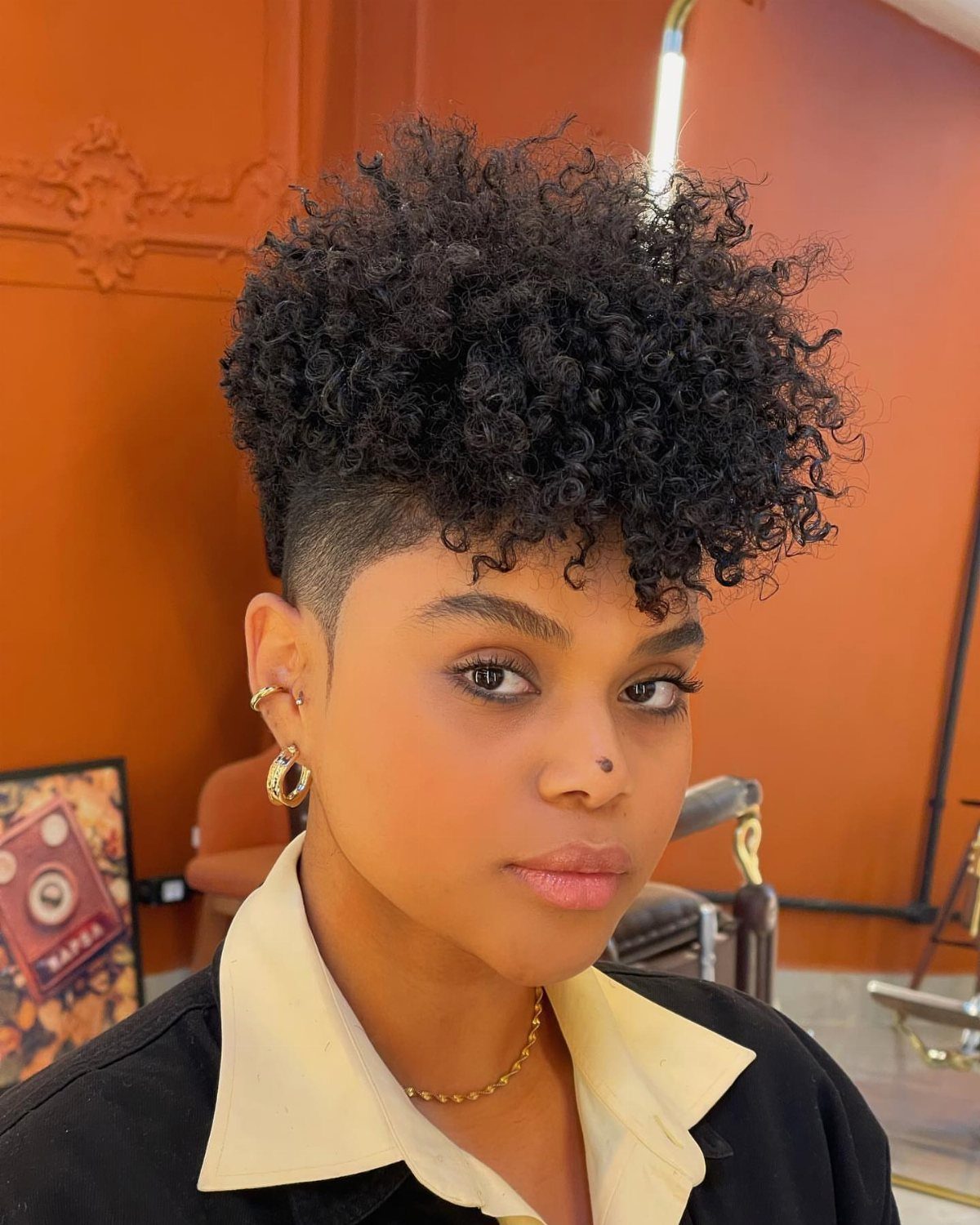 Person with a high curly top and closely tapered sides in a salon