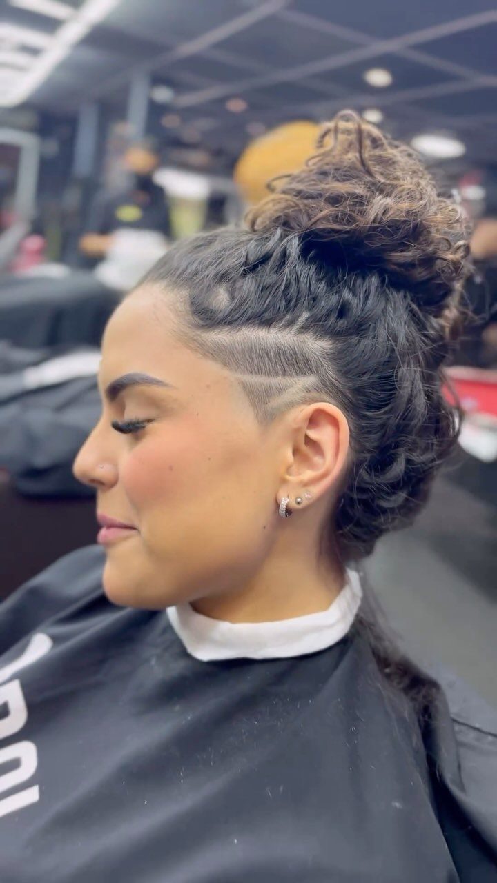 Woman showing a high and tight haircut with shaved sides and a curly bun