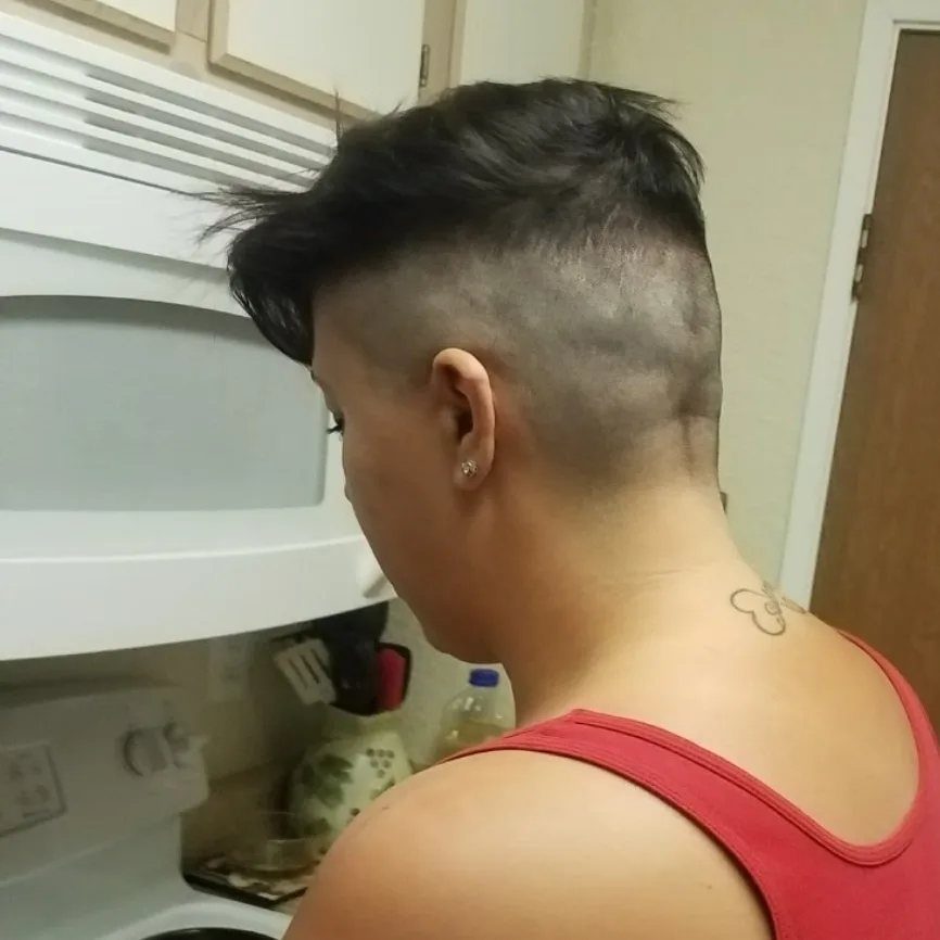 Shaved-sided haircut with longer dark hair on top, seen from behind