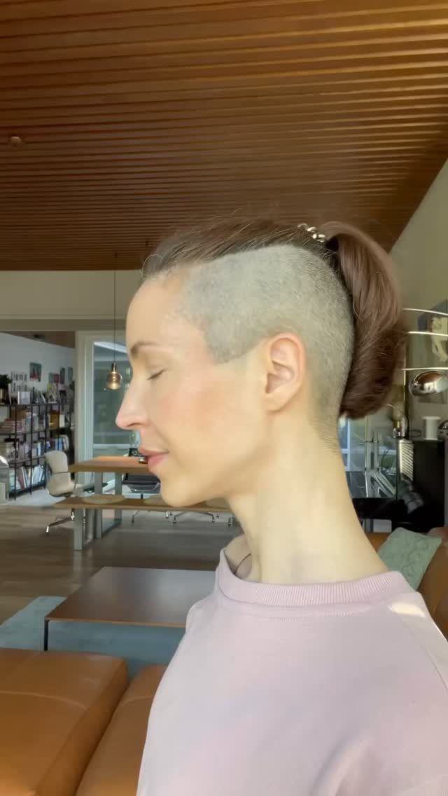 Person with shaved sides and longer top tied back in a bun