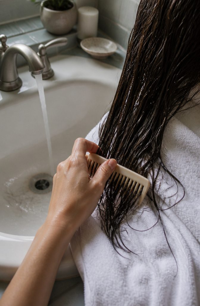Wide tooth comb detangling wet hair over white towel