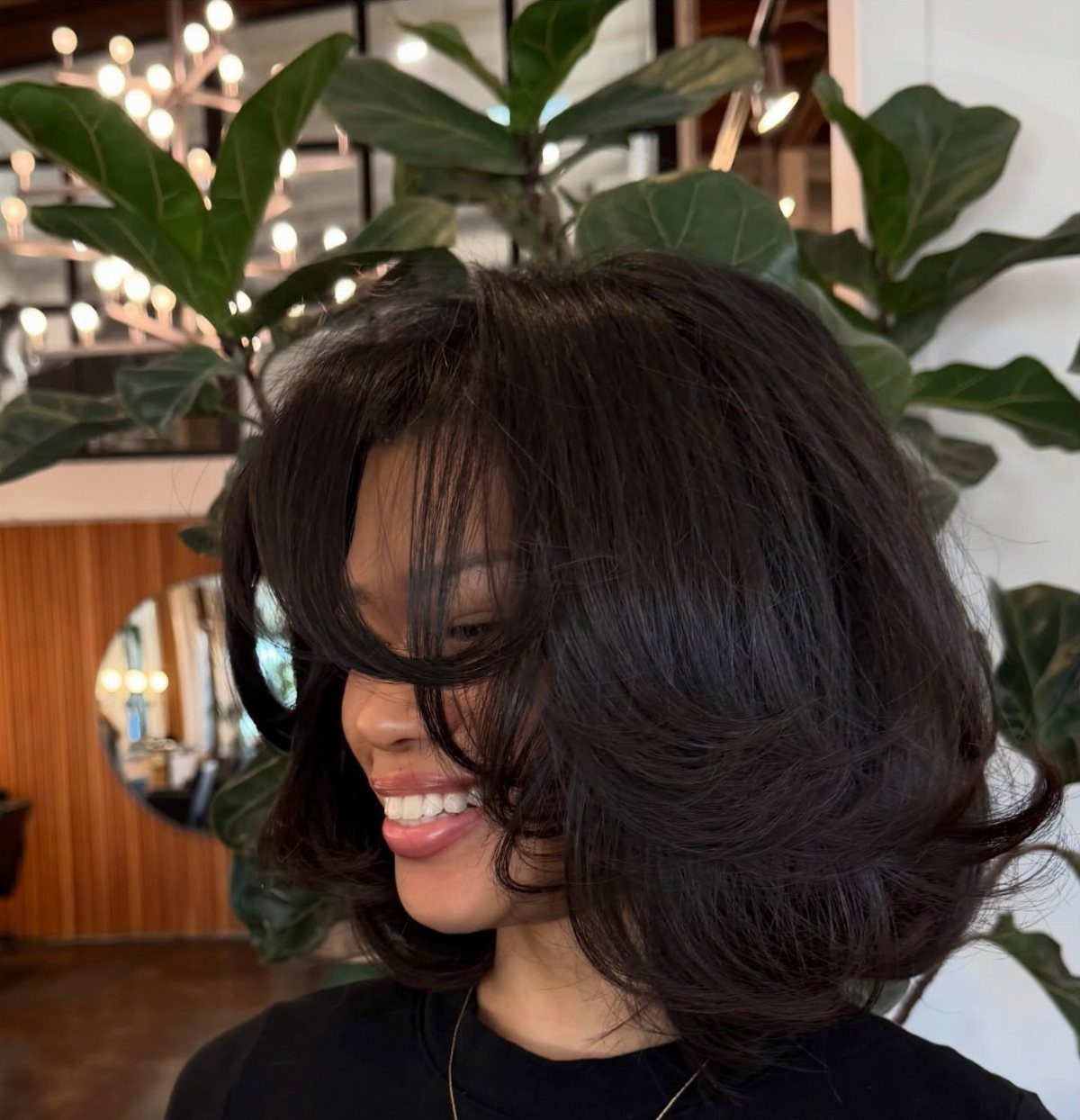 Woman with a voluminous dark bob, curved layers, and long sweeping fringe