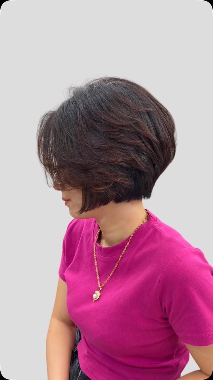 Woman showing a short layered dark brown bixie with sweeping bangs
