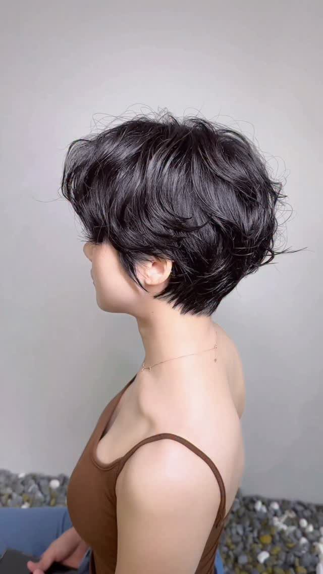 Short dark layered haircut shown from the side on a person