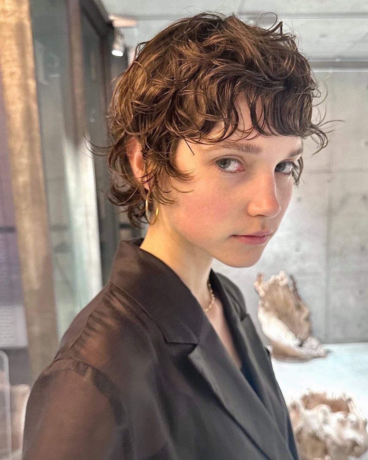 Short wavy pixie bob with layered brown curls and a short fringe