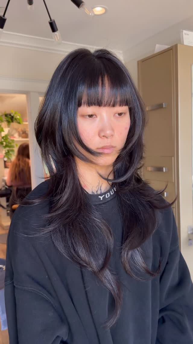 Person displaying long dark layered hair with a straight blunt fringe