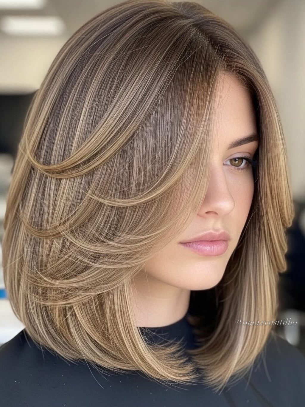 Woman with a layered blonde bob and wispy side-swept bangs