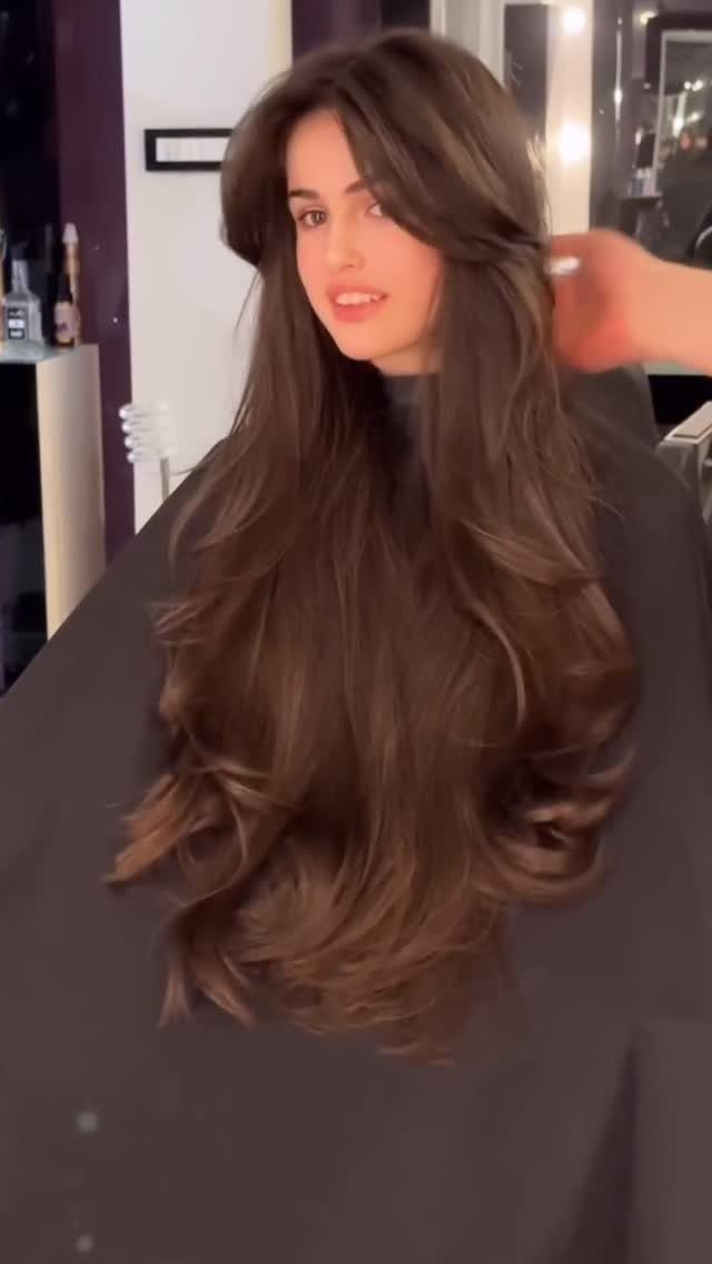 Woman showing long brown butterfly-cut hair with voluminous face-framing layers