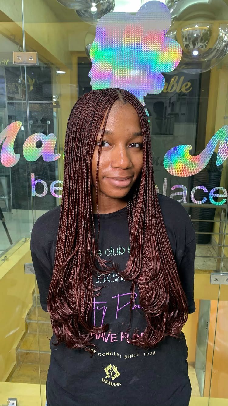 Woman showing long burgundy layered microbraids with curled ends