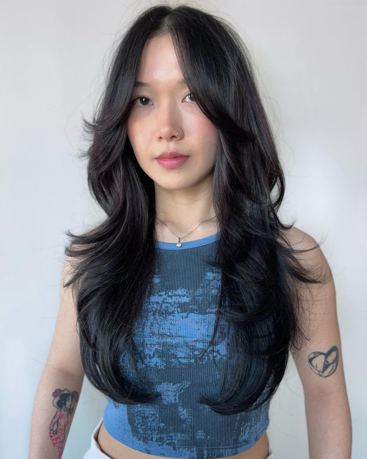 Woman showing long, dark layered hair with soft waves and a center part