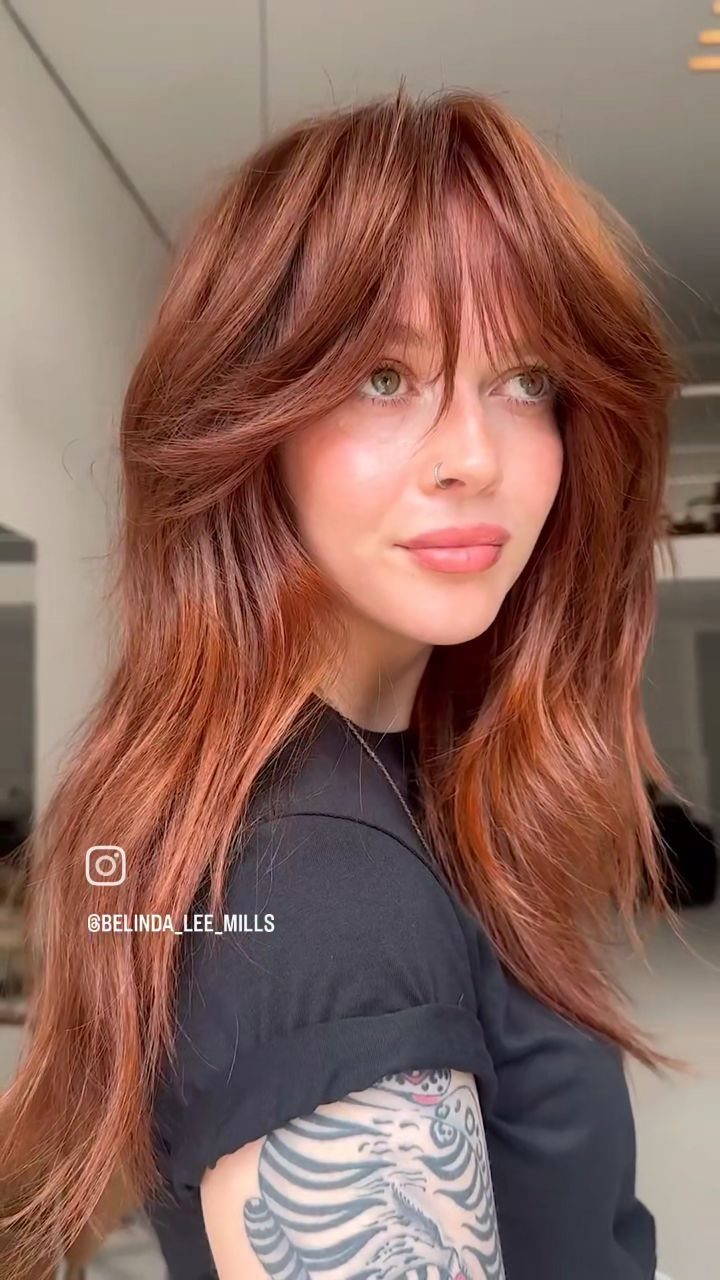 Woman with long copper-red shag cut, tousled layers, and curtain bangs