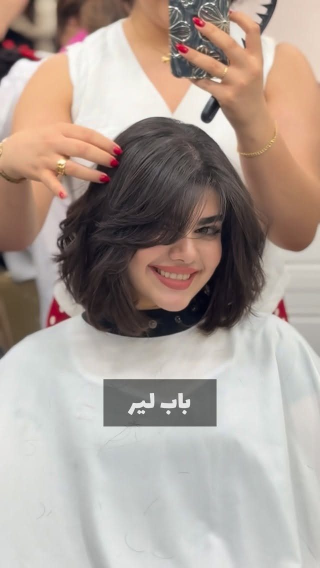 Dark shaggy layered bob with tousled texture and side-swept fringe in a salon
