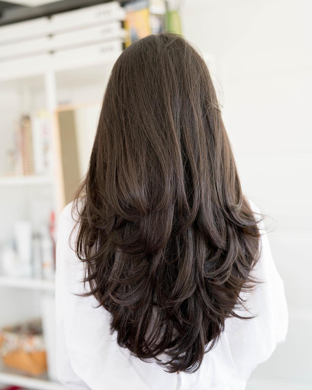 Long dark layered hair curves into a rounded U-shaped perimeter