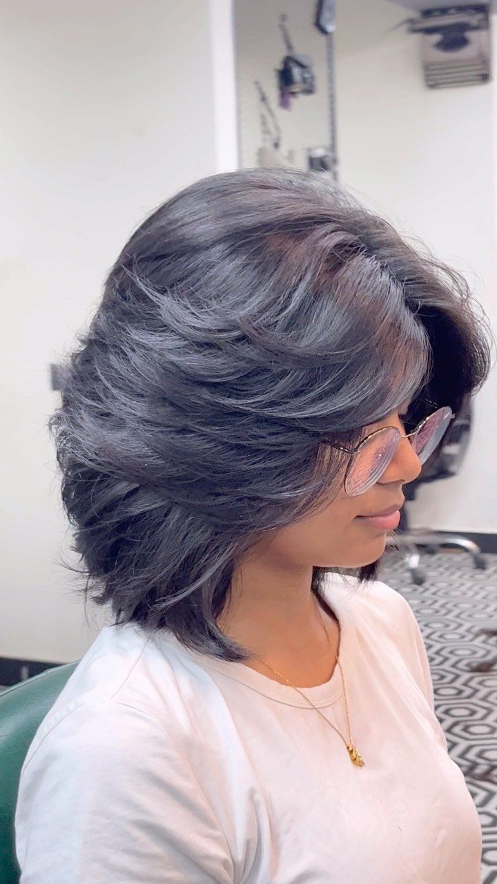 Woman showing a feathered gray layered bob with swept-back, softly textured ends