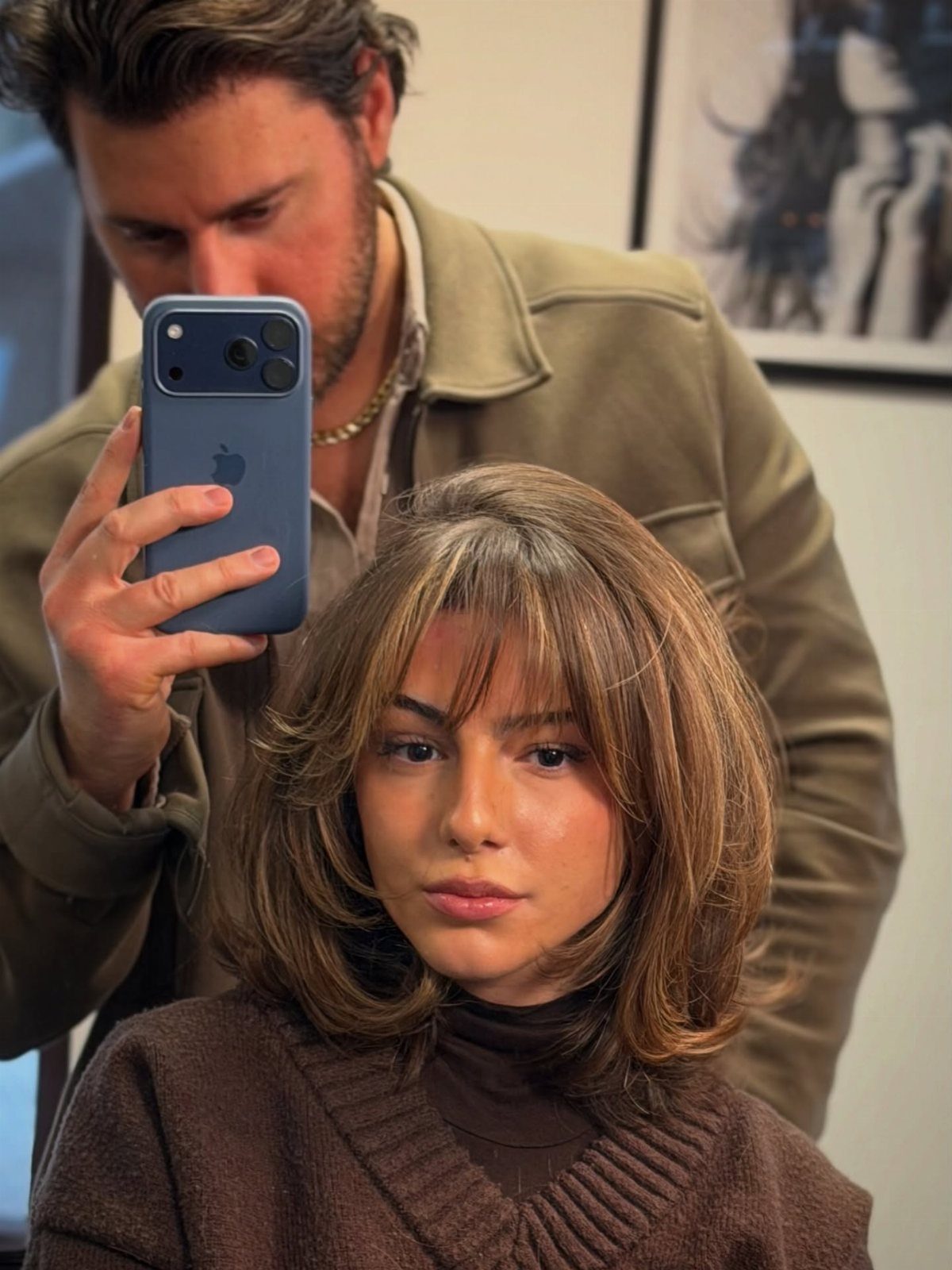 Woman models a layered brown bob with center-parted curtain bangs in a salon