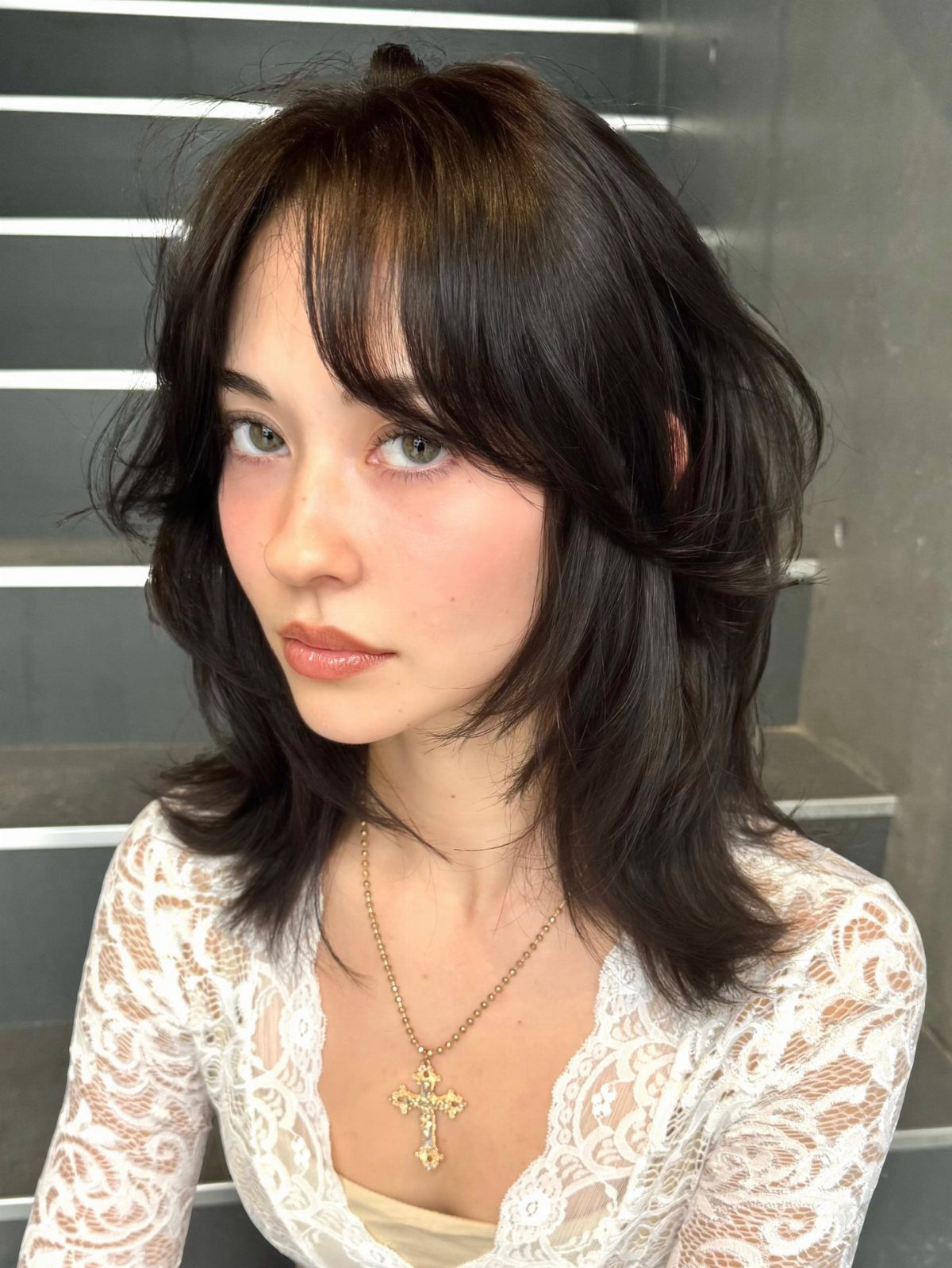 Woman with a dark shaggy layered bob and wispy curtain bangs
