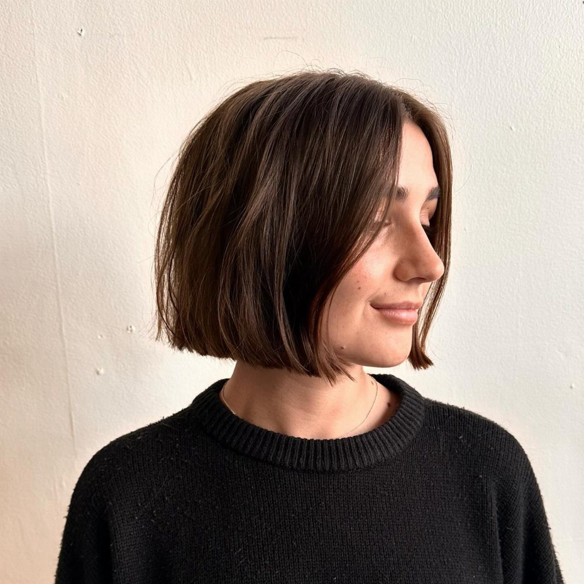 Woman showing a dark blunt chin-length bob with subtle layered face-framing pieces