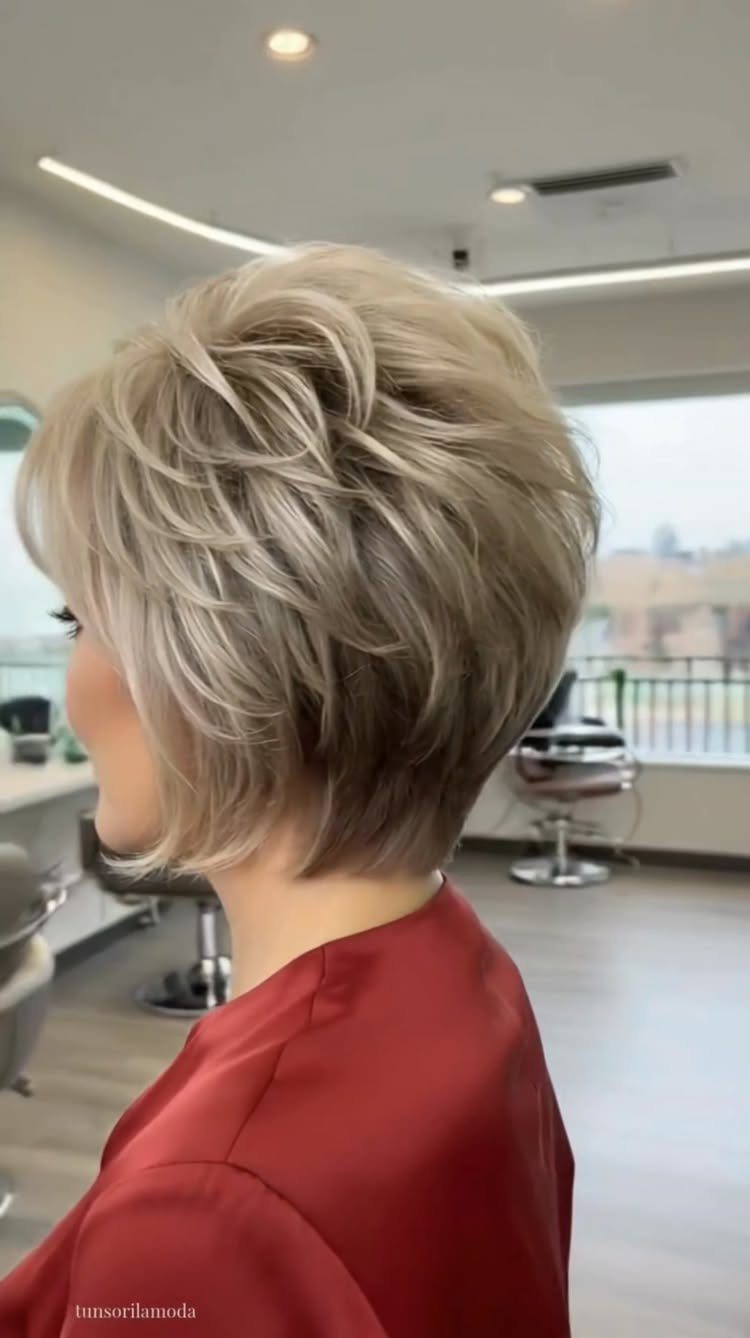 Short layered blonde bob with feathered texture shown in profile at a salon