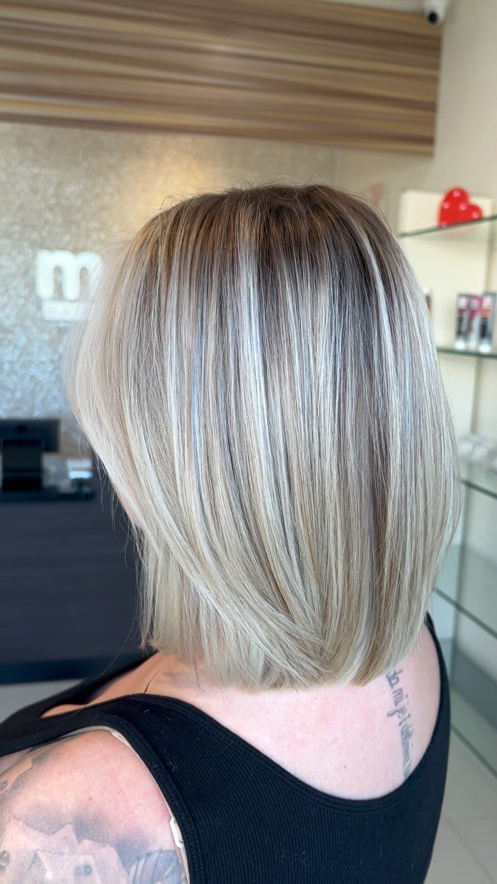 Short bob with dark roots and fine blonde highlights in a salon