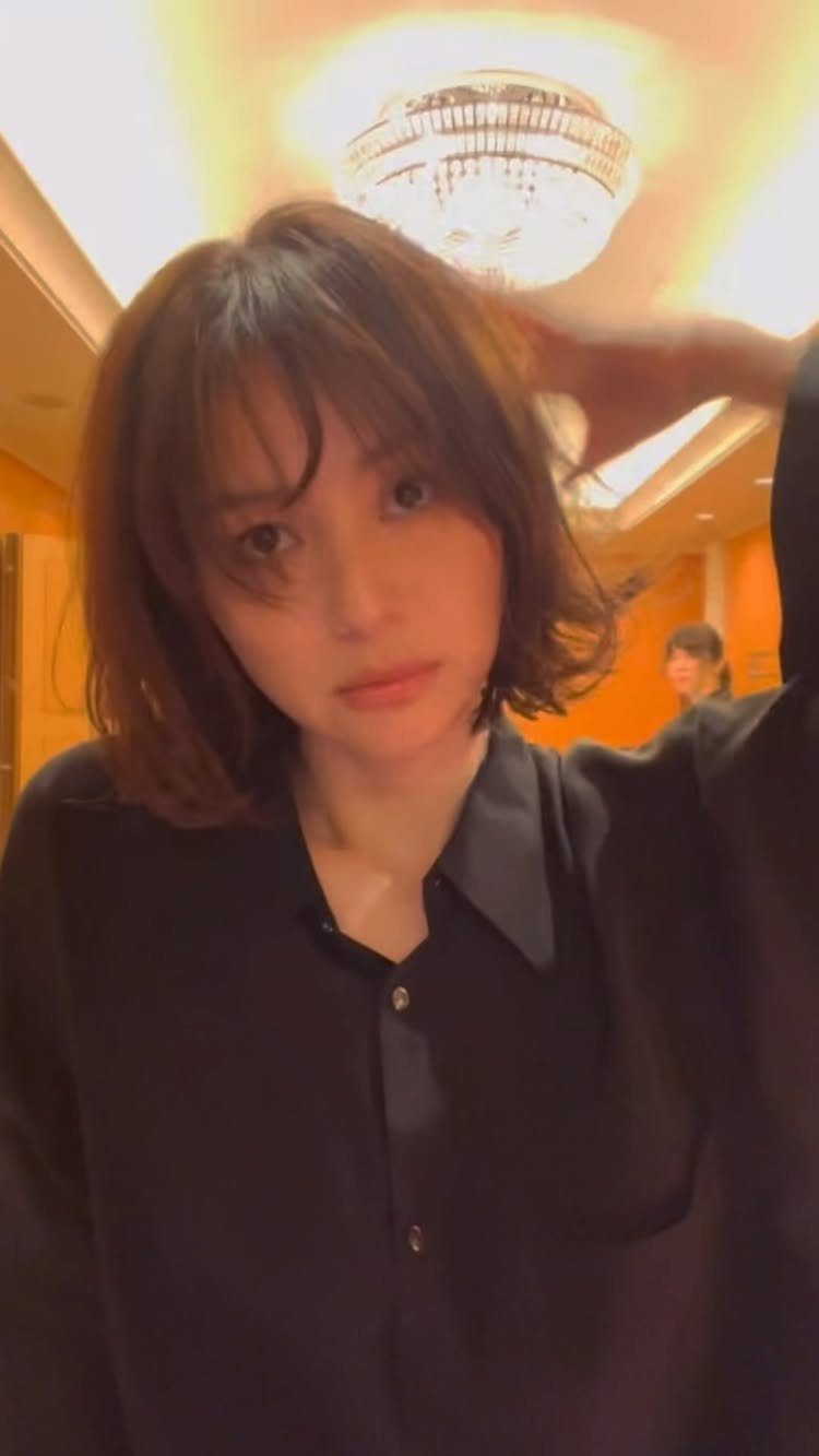 Person showing a tousled short dark bob with bangs indoors