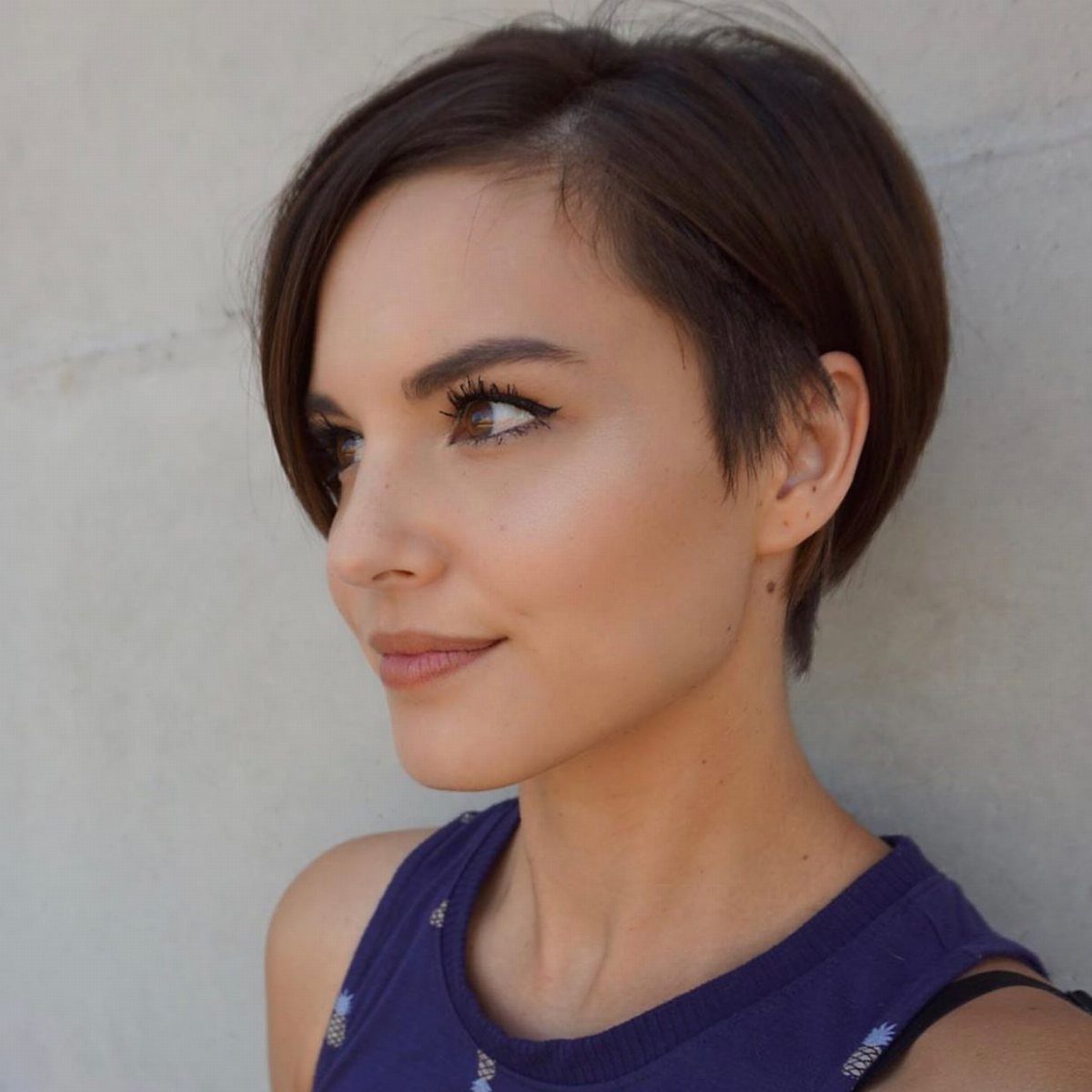 Woman with a short dark brown bob tucked behind one ear