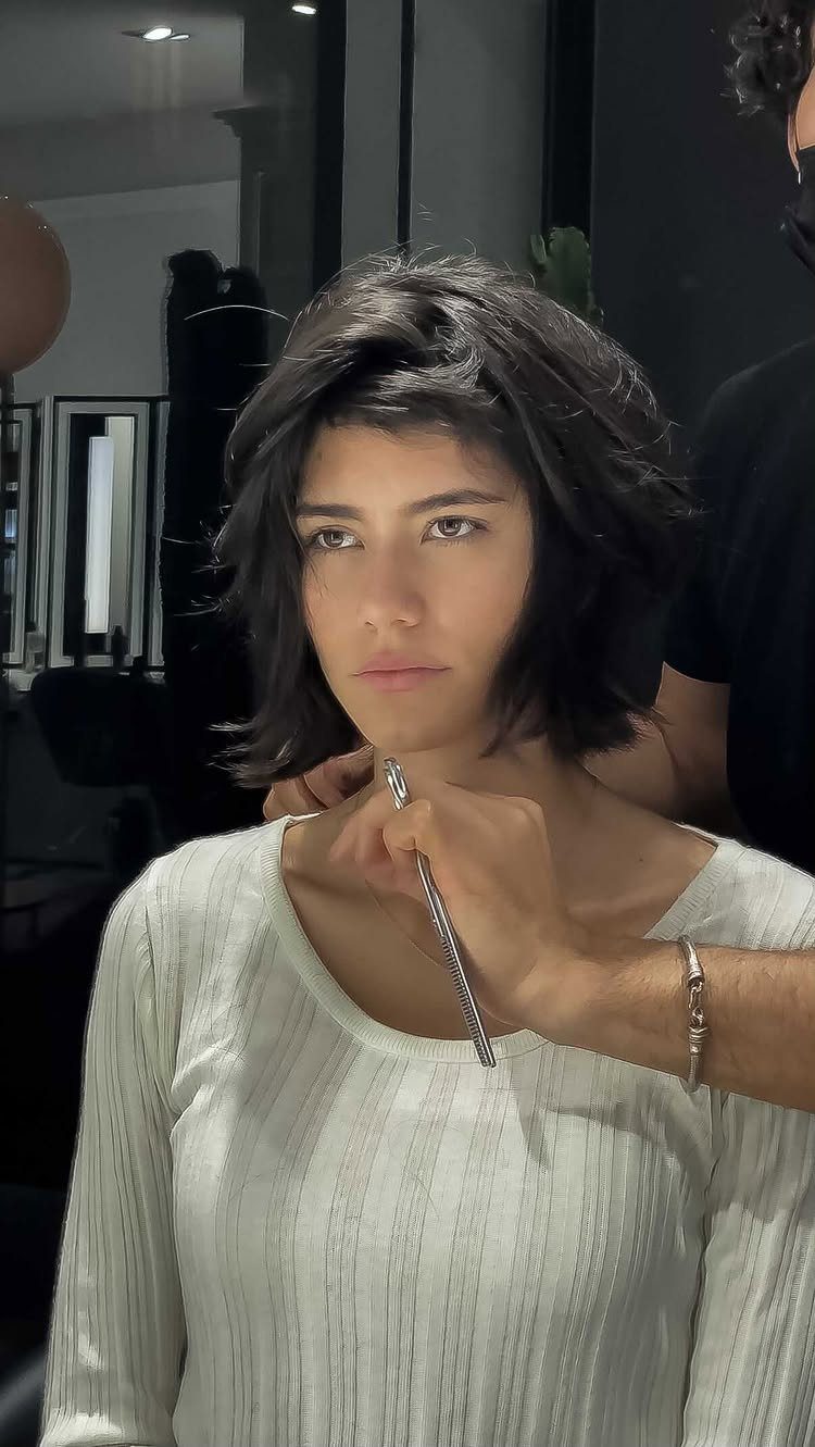 Short dark bob with uneven textured ends being trimmed in a salon