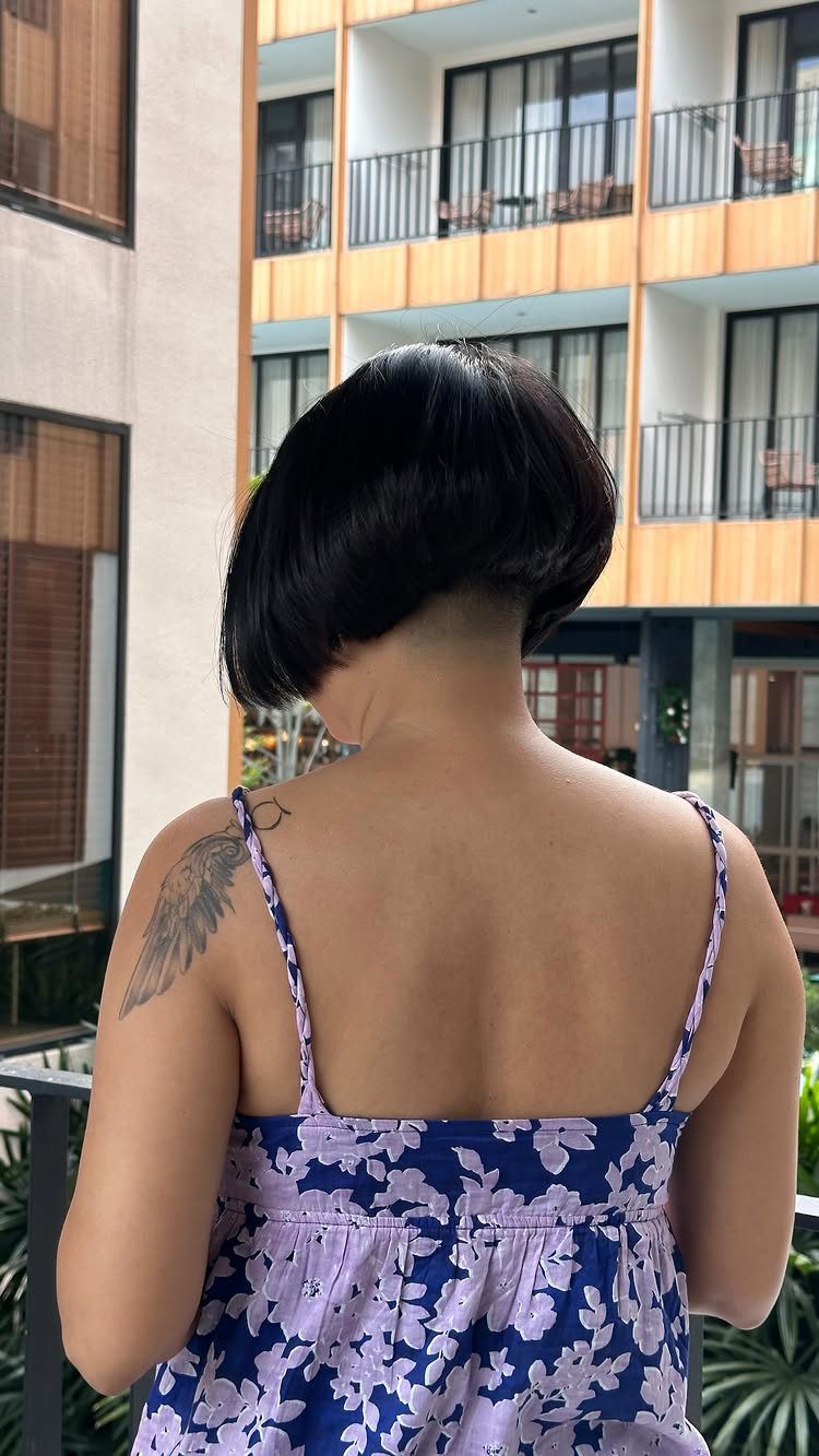 Short dark bob with tapered nape seen from behind against apartment balconies