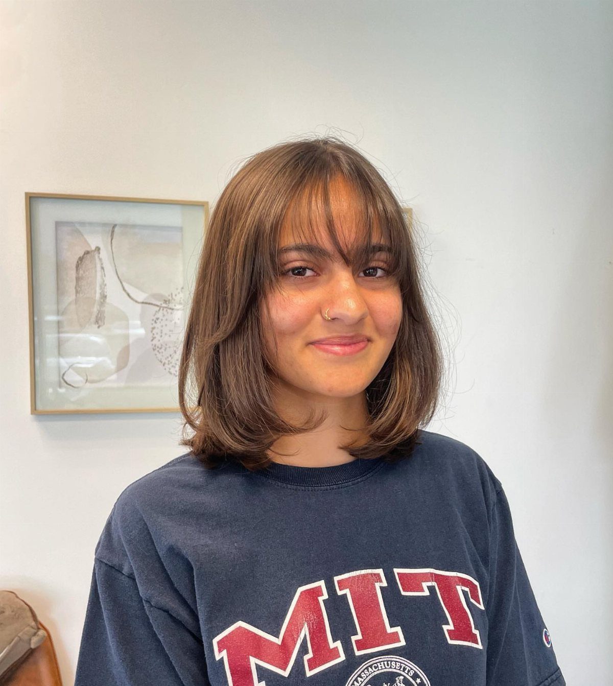 Woman with a brown bob and light, wispy bangs posing indoors
