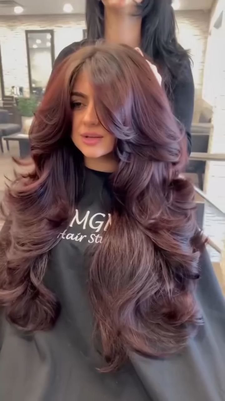 Long auburn butterfly cut with voluminous face-framing layers and curled ends