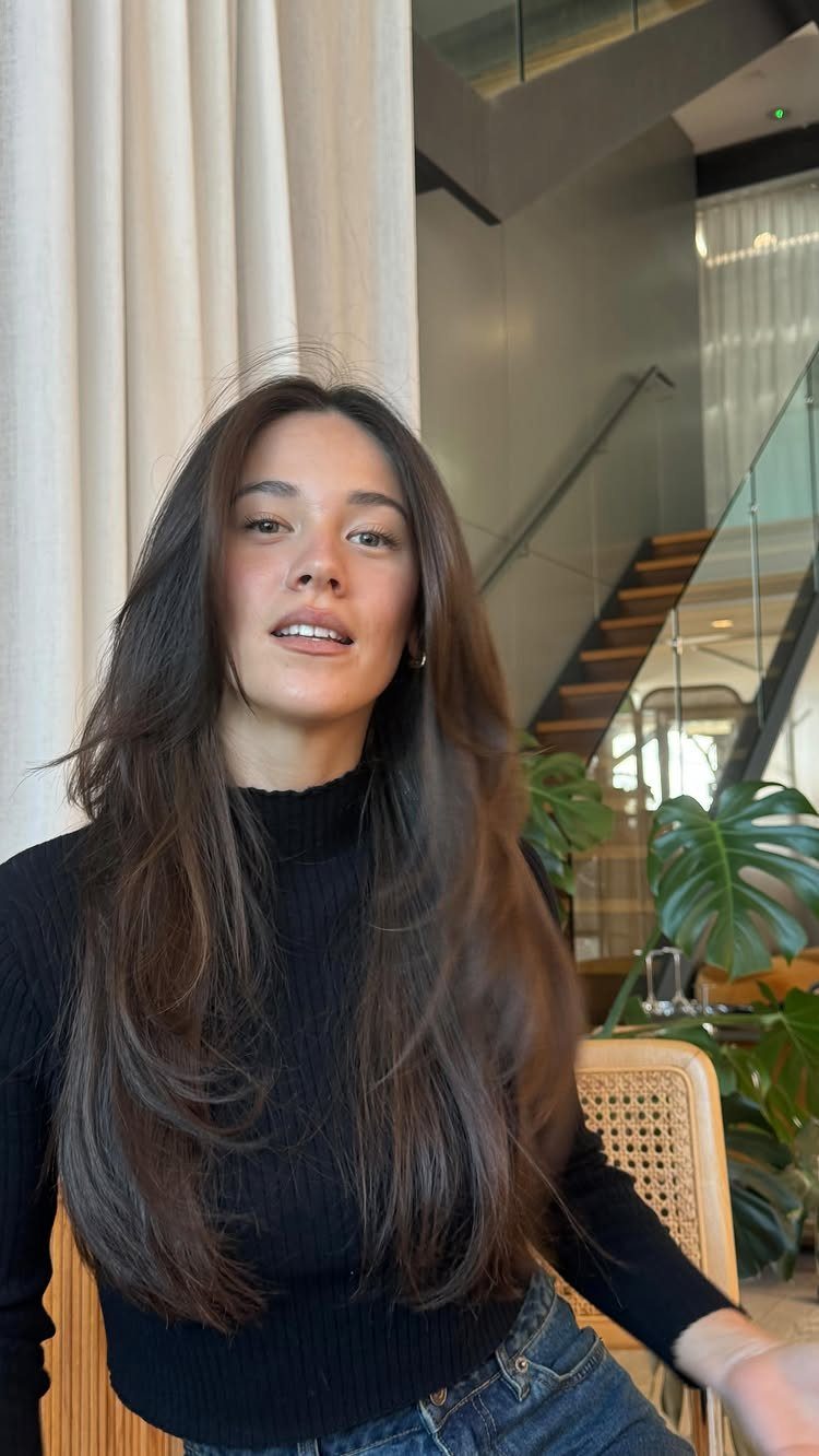 Woman with long dark hair showing soft face-framing layers around her cheeks