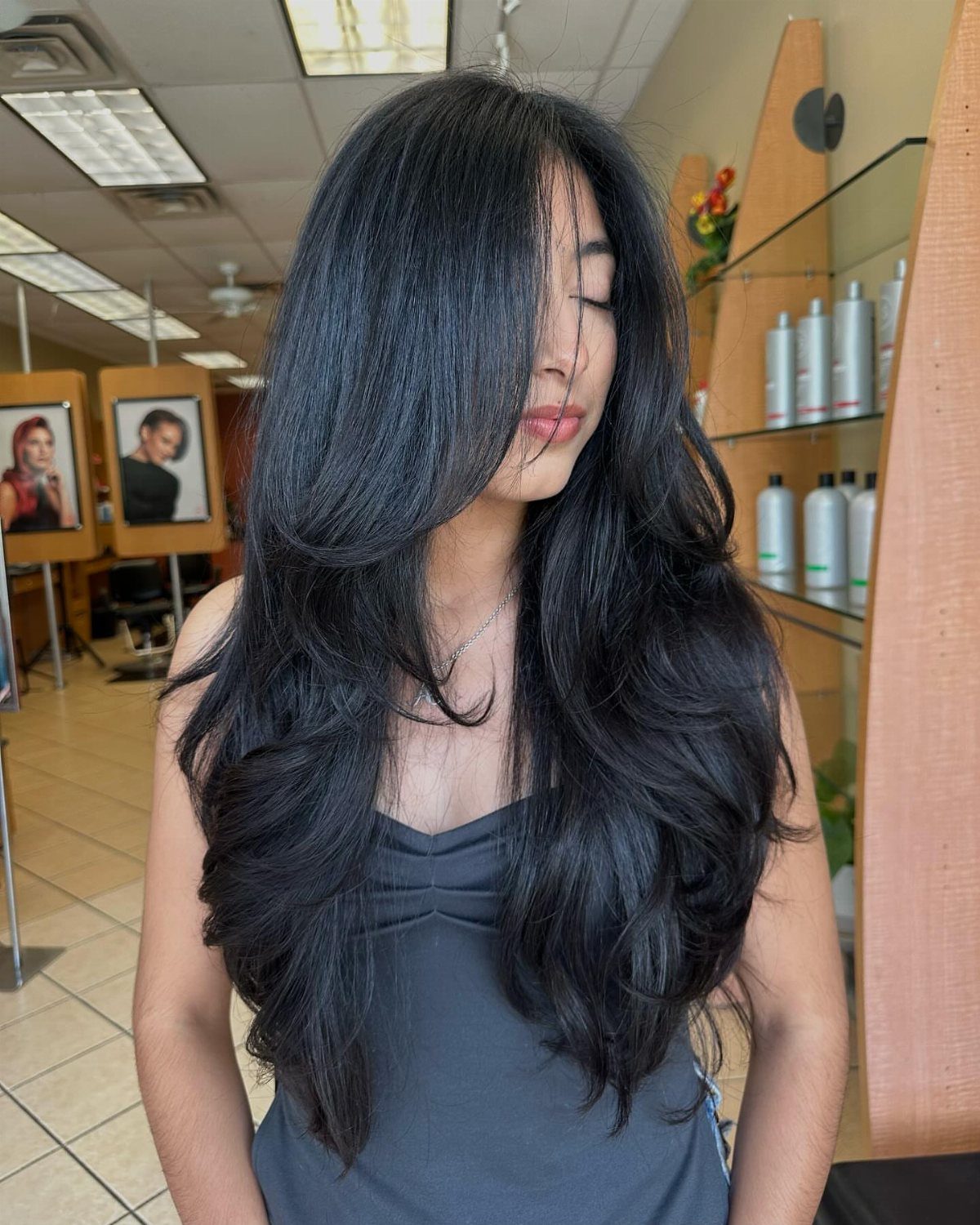Woman displaying long black hair with curved, swoopy layers framing her face