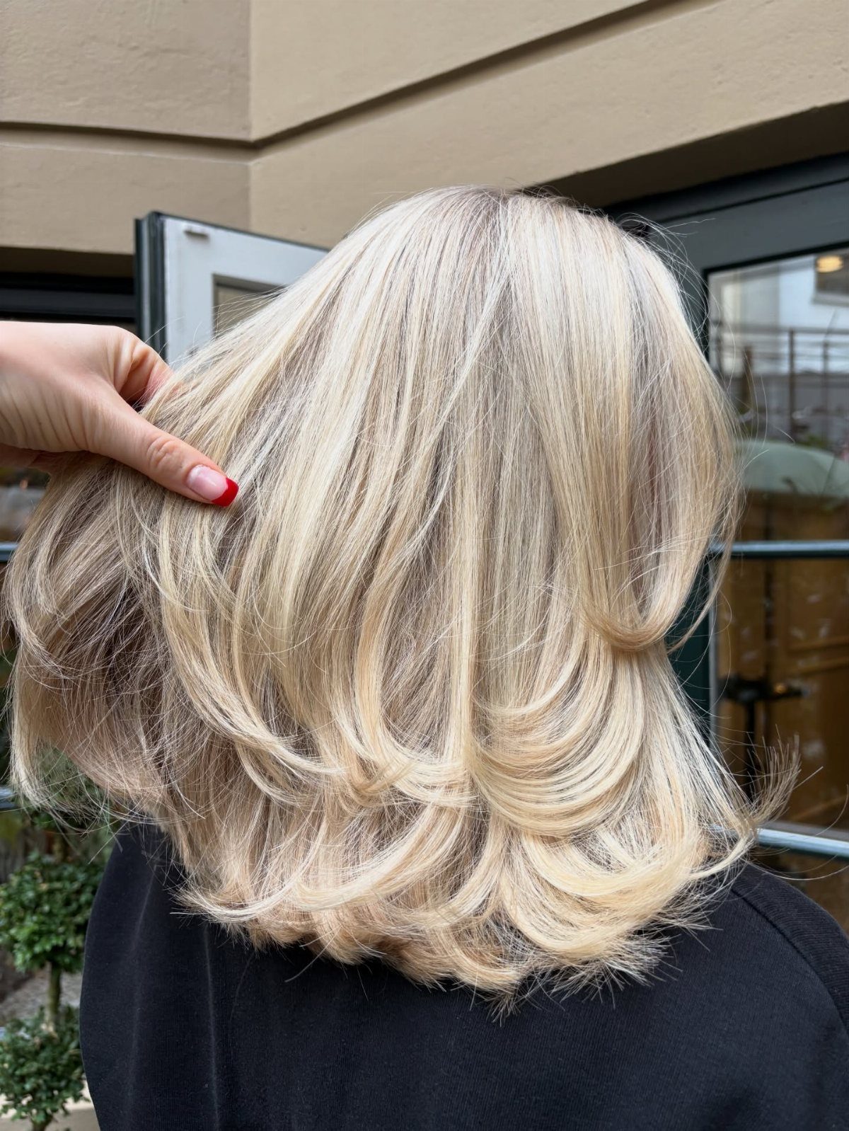 Medium-length layered blonde hair with bright highlights and feathered flipped ends