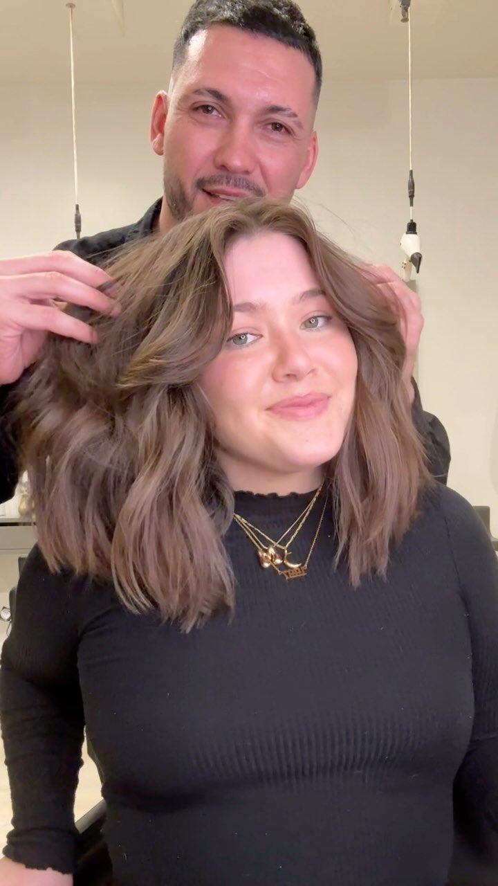 Woman with a layered shoulder-length brown bob as a man lifts her hair