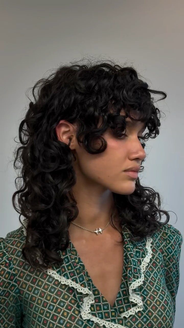 Person with dark collarbone-length curly shag haircut and layered curls