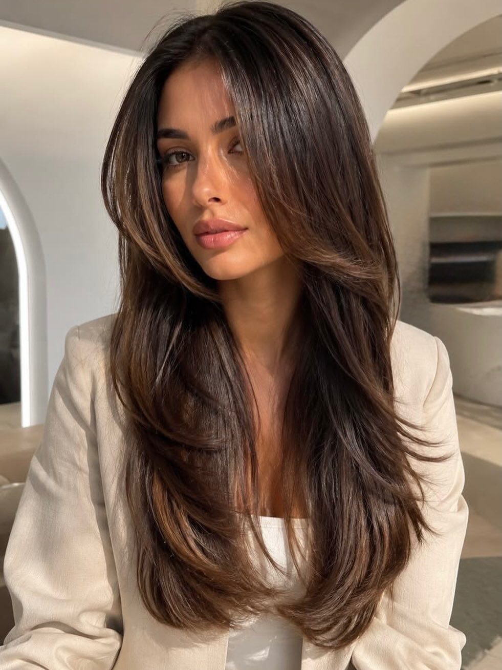 Woman showing long dark brown hair with separated face-framing layers and softly curled ends