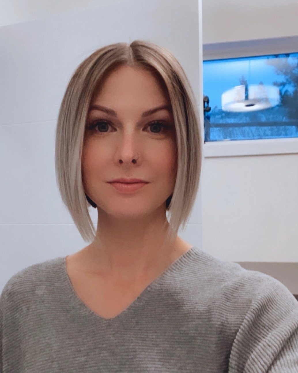 Woman with a straight, center-parted blonde long bob haircut