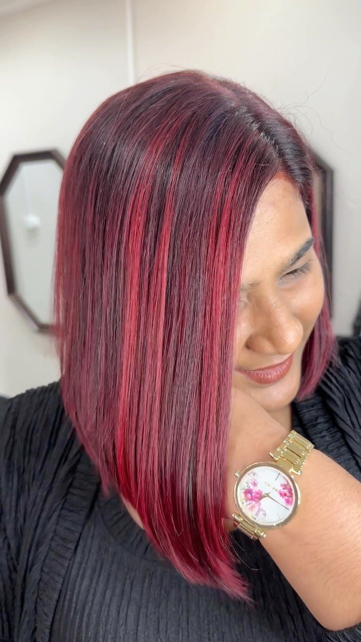 Woman showcasing a sleek burgundy angled long bob haircut with subtle layers