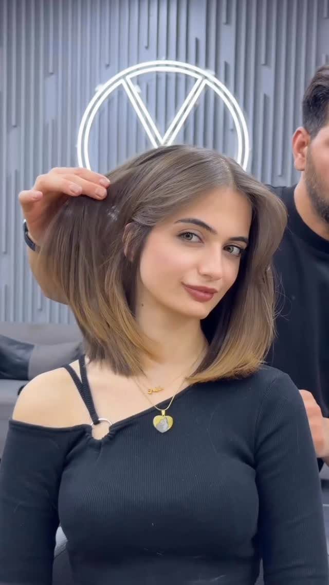 Woman posing with a smooth, side-parted brown shoulder-length bob haircut
