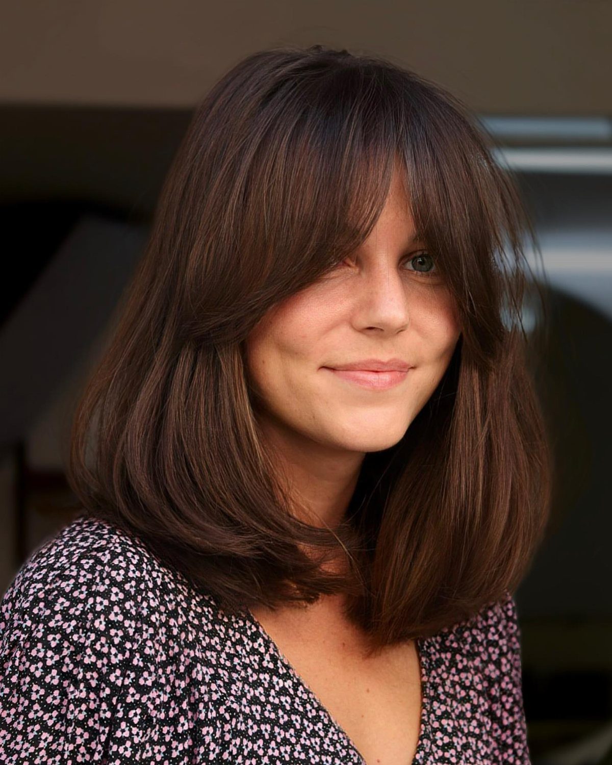 Woman with a dark brown lob and long face-framing curtain bangs